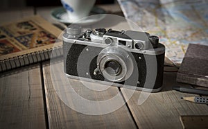 Vintage analogue film camera on a wooden table, map, notepad, pencil.