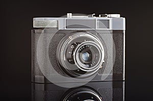 Vintage analogue photo camera isolated with reflection on the black background