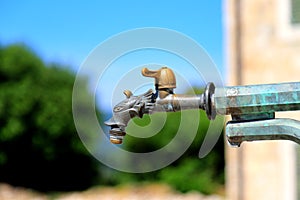 Vintage antique bronze water tap on the fountain in Old city. Belavista Square, Herceg Novi, Montenegro