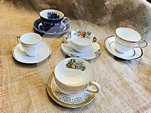 Vintage Antique Collection of Fine Bone China with Gold Trim and Flowers Teacup and Saucer on Burlap Background
