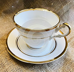 Vintage Antique Fine Bone China with Gold Trim Teacup and Saucer on Burlap Background