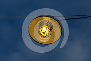 Vintage or antique light bulbs hang at out door with blue sky background at evening light tone.