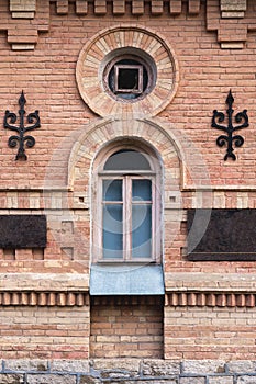 Vintage arched window in the wall of yellow brick. Black glass in a maroon dark red wooden frame. The concept of antique