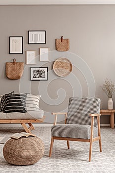 Vintage armchair with chequered pattern next to comfortable beige sofa with pillows in beautiful living room interior