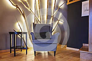 Vintage armchair in living room with homemade tree branch led-lamp on wall photo