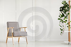 Vintage armchair next to an empty wall in a daily room interior. Real photo. Place your poster