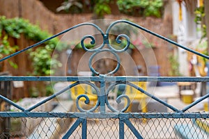 Vintage artistic green wrought iron gate with peeling paint and rust revealing blurred garden