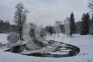 Vintage `Ð¡ast Iron` bridge over Slavyanka river. The Winter landscape. Pavlovsk Palace Park. Saint-Petersburg, Russia