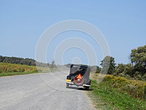 Vintage automobile cruising on dirt road in summer day