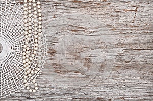 Vintage background with bead necklace and lace on the old wood