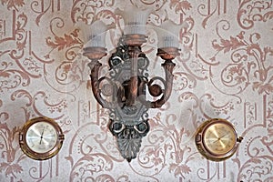 Vintage background with a beautiful sconce and barometers on the wall