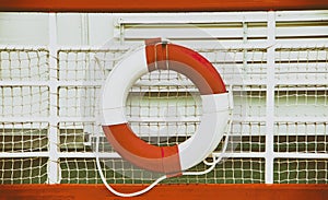 Vintage background with rescue circle on boat. Lifebuoy is mounted on a ship. The circle is red and white