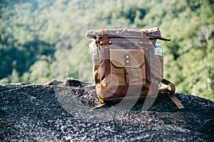 Vintage bagpack put on peak of mountain photo