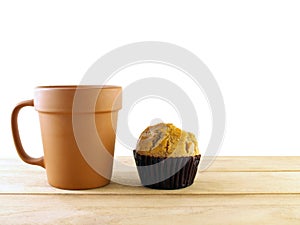 vintage baked clay coffee cup and banana cupcake in dark brown paper cup on wooden table top isolated on white background