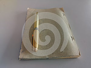 A Vintage Ball Pen on A Brown Notebook isolated with White Background