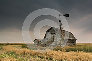 Vintage barn, bins and windmill under ominous dark skies in Saskatchewan, Canada