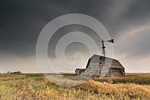 Vintage barn, bins and windmill under ominous dark skies in Saskatchewan, Canada