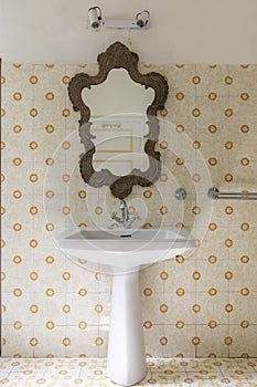Vintage bathroom in ancient villa with tiles, sink and antique mirror