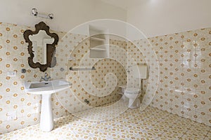 Vintage bathroom in ancient villa with tiles, sink, antique mirror and toilet