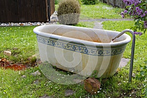 Vintage bathtub outside in garden with running rusty water