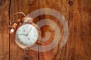 Vintage, beautiful alarm clock made from gold metal on a wooding surface. Good morning. Awakening. top view