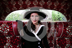 Vintage beautiful woman wearing hat sitting on retro bus