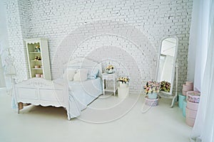 Vintage bed with pillows and a vase of flowers stand on the bedside table 2