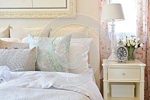 Vintage bedroom interior with flower pillows and decorative table lamp