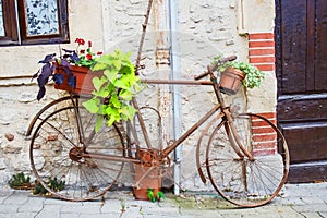 Vintage bicycle with basket of flowers in front of the old rustic house in France, Europe