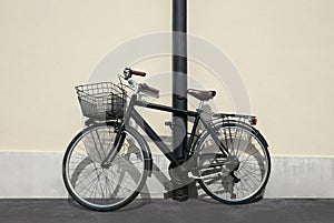 Vintage bicycle with basket locked to street post outdoors