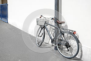 Vintage bicycle with basket locked to street post outdoors