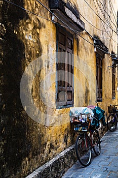 Vintage Bicycle by a yellow ancient wall of an old building in the Ancient City of Hoi An, Vietnam.Vertical, portrait view