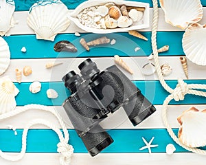 Vintage binoculars, shells, small fishing boat and sailor rope on a wooden background. Sea concept. Overhead view.