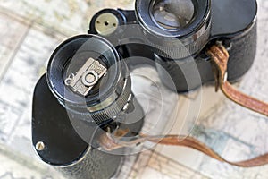 Vintage binoculars and silver camera decoration on old map pages