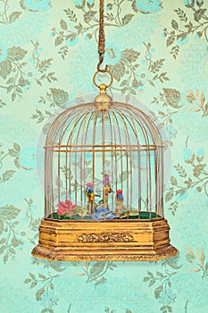 Vintage birdcage with old figurine birds in front of wallpaper with flower pattern