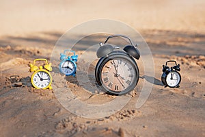 Vintage black alarm clock on autumn leaves. Time change abstract photo.