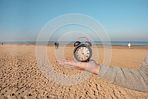 Vintage black alarm clock on autumn leaves. Time change abstract photo.