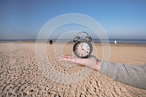 Vintage black alarm clock on autumn leaves. Time change abstract photo.