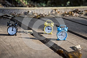 Vintage black alarm clock on autumn leaves. Time change abstract photo. Daylight saving time