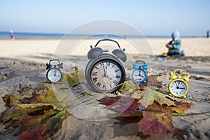 Vintage black alarm clock on autumn leaves. Time change abstract photo. Daylight saving time