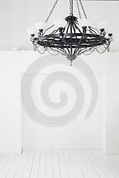 Vintage black chandelier with candles in an empty room