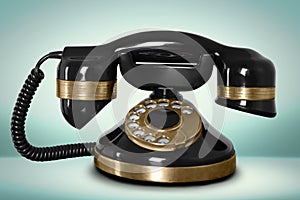 Vintage black corded telephone on pale turquoise background