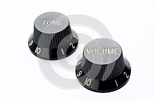 Two vintage black guitar volume and tone knobs on white background