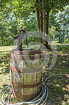 Vintage black Hand Crank Manual Water Pumping from a wood barrel