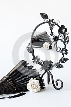 Vintage black mirror with white roses and hand fan on white background. Vintage black mirror with white roses and hand fan on