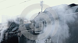 Vintage black steam locomotive. Historic train runs through fields. Vehicle