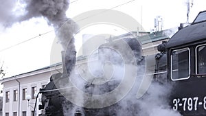 Vintage black steam locomotive. Historic train runs through fields. Vehicle