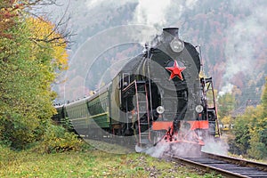 Vintage black steam locomotive train with wagons on railway.