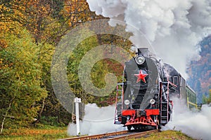 Vintage black steam locomotive train with wagons on railway.