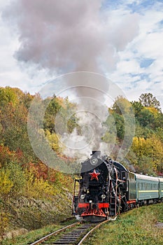 Vintage black steam locomotive train with wagons on railway.